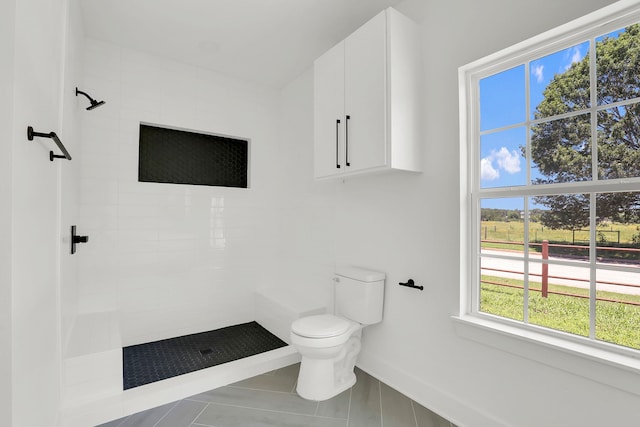 bathroom with a tile shower, tile patterned flooring, and toilet