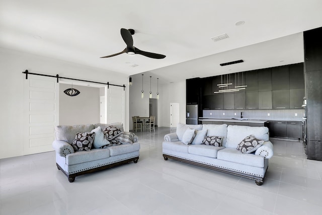 tiled living room with ceiling fan, sink, and a barn door