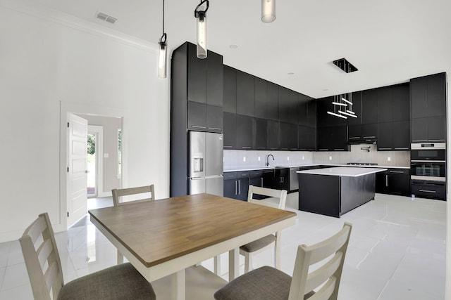 kitchen featuring light tile patterned floors, tasteful backsplash, a kitchen island, decorative light fixtures, and stainless steel appliances