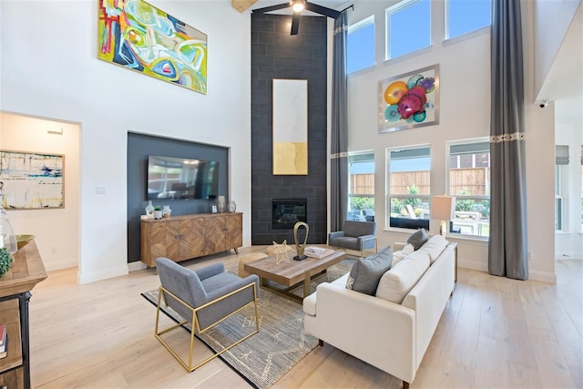 living room featuring a fireplace, a towering ceiling, and light hardwood / wood-style flooring