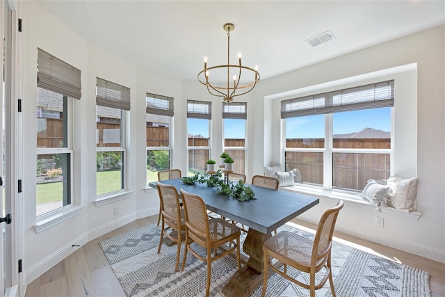 dining area with light hardwood / wood-style flooring and a notable chandelier