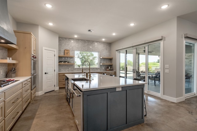 kitchen featuring a healthy amount of sunlight, concrete floors, a kitchen island with sink, and tasteful backsplash