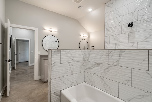 bathroom with tiled shower / bath combo, vanity, vaulted ceiling, and concrete flooring