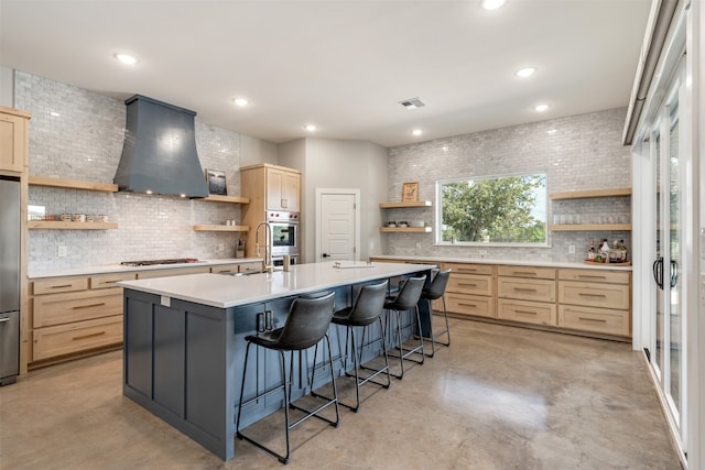 kitchen featuring a kitchen breakfast bar, premium range hood, light brown cabinetry, and an island with sink