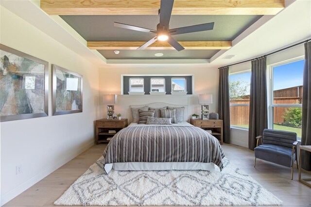 bedroom with ceiling fan, light wood-type flooring, and beam ceiling