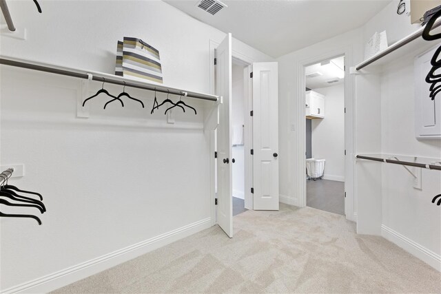 walk in closet with light carpet