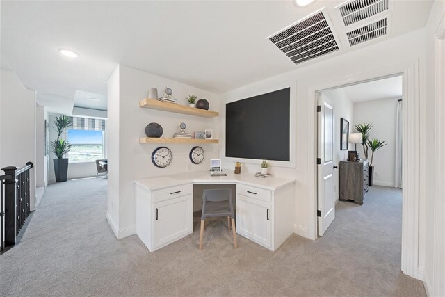 home office with light carpet and built in desk