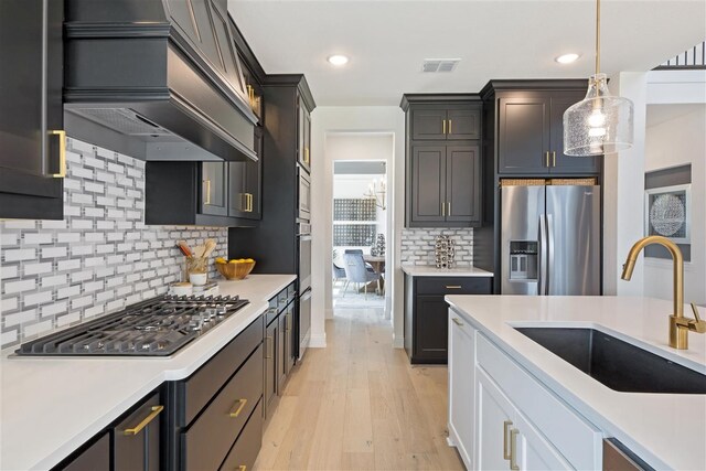 kitchen with decorative backsplash, white cabinetry, stainless steel appliances, light hardwood / wood-style flooring, and sink