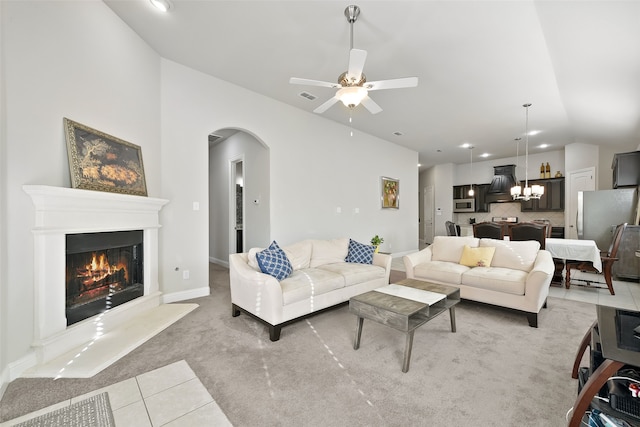 tiled living room with ceiling fan with notable chandelier