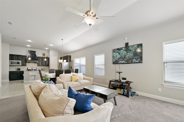 carpeted living room with plenty of natural light, ceiling fan with notable chandelier, and vaulted ceiling