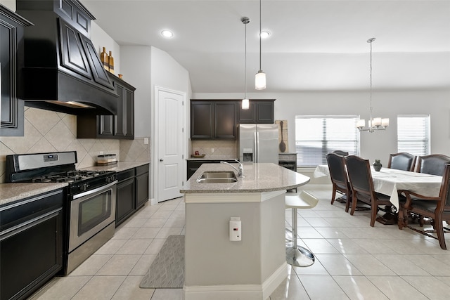 kitchen featuring an island with sink, sink, an inviting chandelier, appliances with stainless steel finishes, and decorative light fixtures