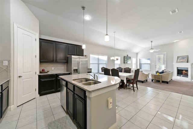 kitchen with sink, plenty of natural light, stainless steel appliances, ceiling fan with notable chandelier, and vaulted ceiling