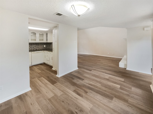 kitchen with a textured ceiling, white cabinetry, backsplash, hardwood / wood-style floors, and white dishwasher