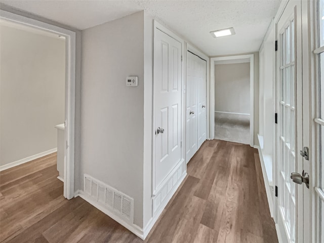 hallway with wood-type flooring and a textured ceiling