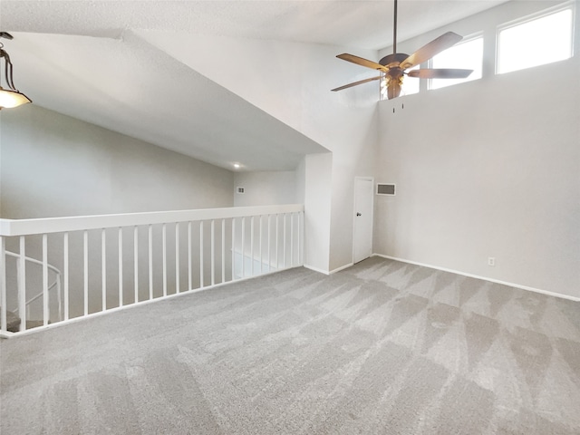 empty room with ceiling fan, light colored carpet, and high vaulted ceiling