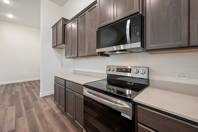 kitchen with appliances with stainless steel finishes, dark hardwood / wood-style floors, and dark brown cabinets