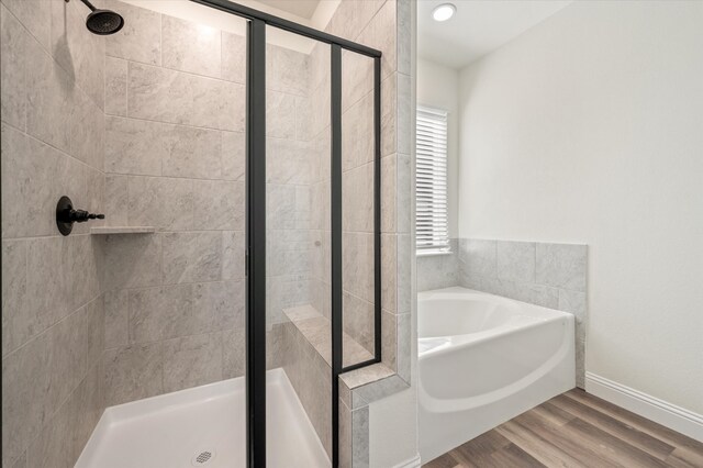 bathroom featuring wood-type flooring and shower with separate bathtub