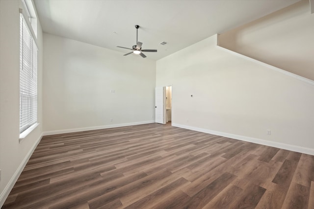 unfurnished living room featuring a towering ceiling, ceiling fan, and dark wood-type flooring