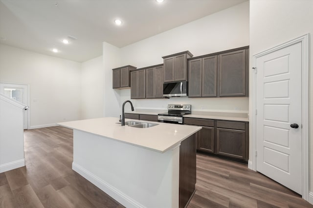 kitchen featuring an island with sink, sink, appliances with stainless steel finishes, and dark wood-type flooring