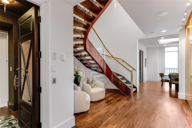 staircase with baseboards, wood finished floors, and recessed lighting