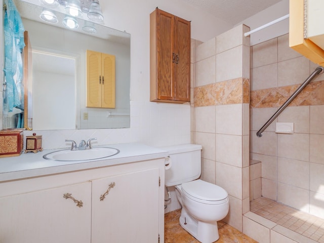 full bath with toilet, a stall shower, vanity, and tile walls