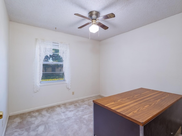 unfurnished office with carpet floors, baseboards, a ceiling fan, and a textured ceiling