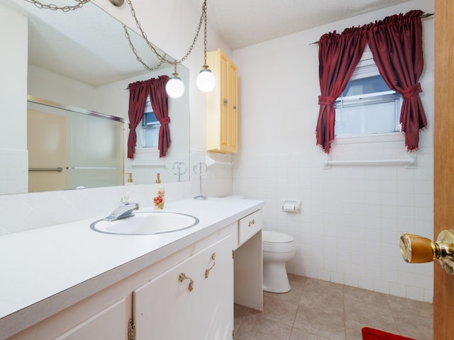 bathroom with tile patterned flooring, toilet, a wainscoted wall, vanity, and tile walls