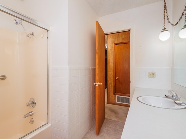 bathroom with a wainscoted wall, tile walls, bathtub / shower combination, visible vents, and tile patterned flooring