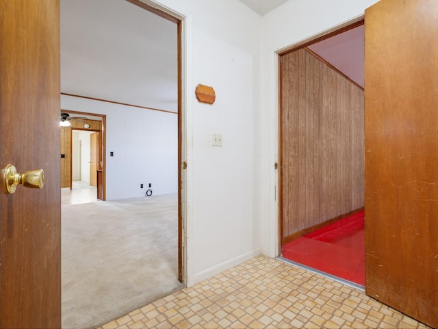 corridor featuring light colored carpet and wooden walls