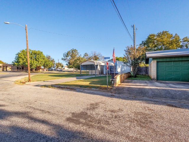 view of yard with a garage, driveway, and fence