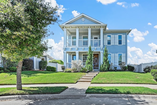 neoclassical home featuring a front yard, a balcony, and a porch