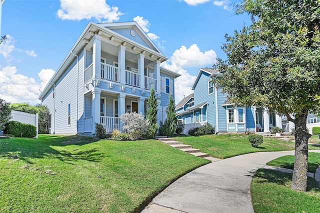 greek revival house with a balcony, a front lawn, and covered porch