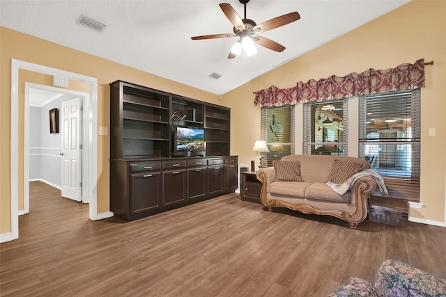 living room featuring a textured ceiling, lofted ceiling, dark wood-type flooring, and ceiling fan