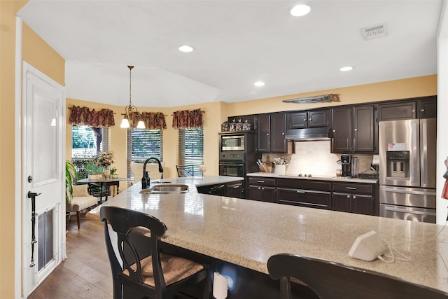 kitchen featuring hanging light fixtures, a chandelier, black appliances, a breakfast bar, and dark hardwood / wood-style flooring