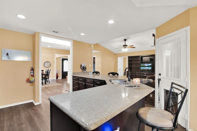 kitchen featuring light stone counters, dark hardwood / wood-style floors, sink, a kitchen breakfast bar, and ceiling fan