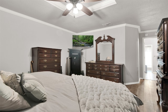 bedroom with a textured ceiling, wood-type flooring, ornamental molding, and ceiling fan