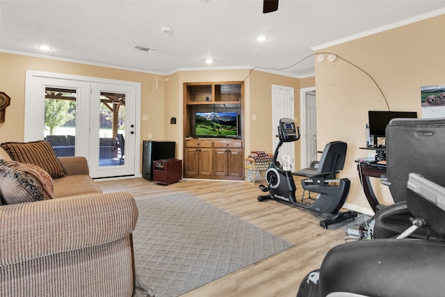 workout room with a textured ceiling, ornamental molding, and light hardwood / wood-style flooring