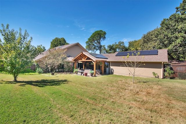 rear view of house with solar panels and a lawn