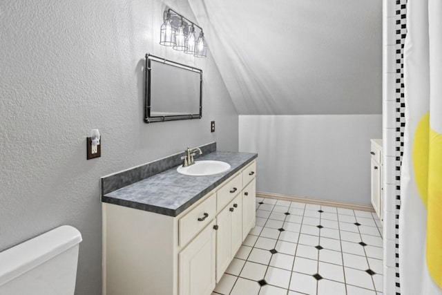 bathroom featuring tile patterned flooring, vanity, toilet, and lofted ceiling