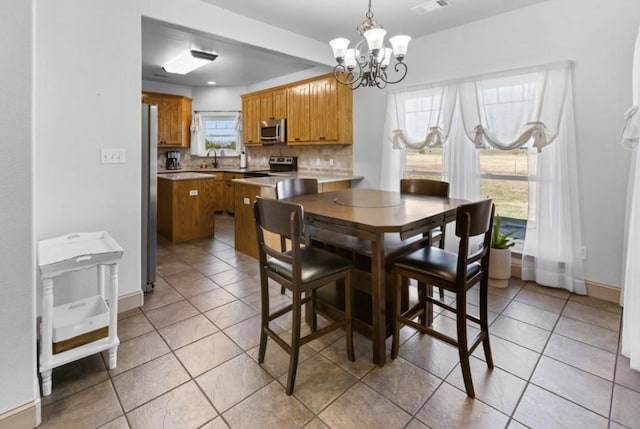 dining room with light tile patterned floors, a notable chandelier, and sink