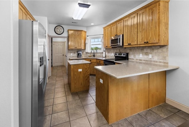 kitchen featuring a center island, stainless steel appliances, backsplash, kitchen peninsula, and tile patterned floors