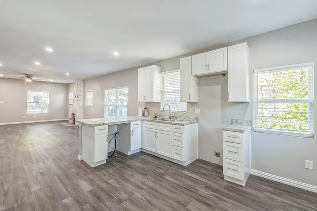 interior space with kitchen peninsula, white cabinetry, light hardwood / wood-style flooring, sink, and light stone counters