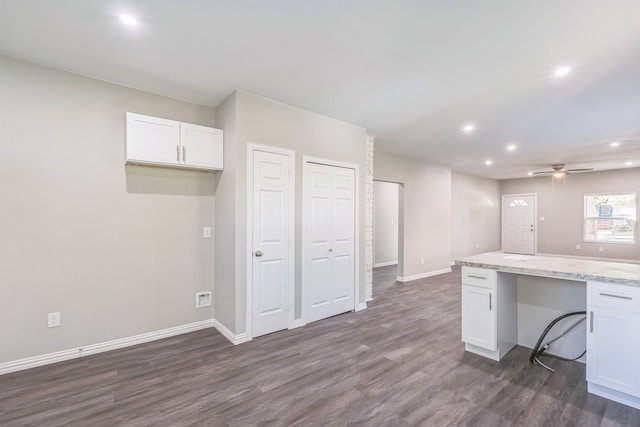 kitchen with light stone countertops, sink, kitchen peninsula, hardwood / wood-style floors, and white cabinetry