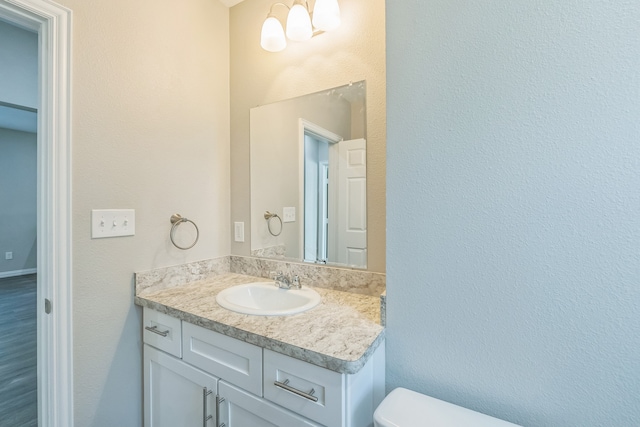 bathroom with toilet, vanity, and wood-type flooring