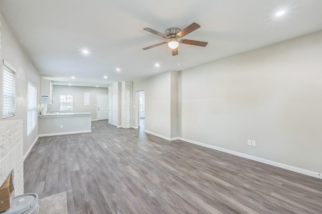 unfurnished living room featuring dark hardwood / wood-style flooring, a brick fireplace, and ceiling fan