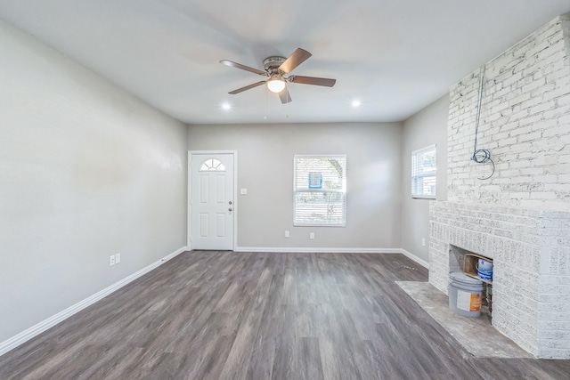 unfurnished living room featuring ceiling fan, hardwood / wood-style flooring, sink, and a fireplace