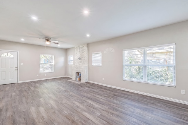 unfurnished living room featuring a brick fireplace, dark hardwood / wood-style floors, and ceiling fan