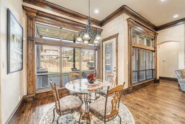 dining space with ornamental molding, an inviting chandelier, and wood-type flooring