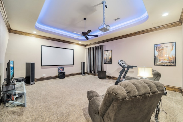 home theater room with ceiling fan, a tray ceiling, ornamental molding, and carpet