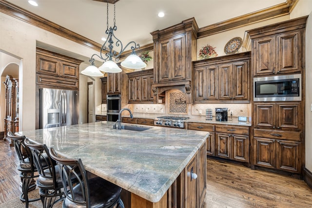 kitchen featuring wood-type flooring, a large island, a chandelier, stainless steel appliances, and crown molding